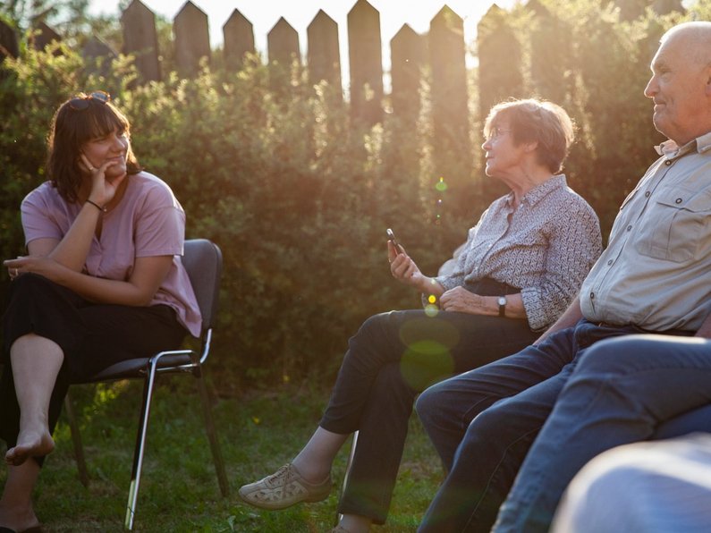 Mehrere Personen der Neuen Auftraggeber von Wietstock sitzen in der Abendsonne und sprechen miteinander