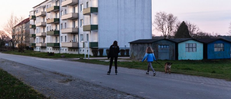 People on a street in front of a block of apartments in Züsedom