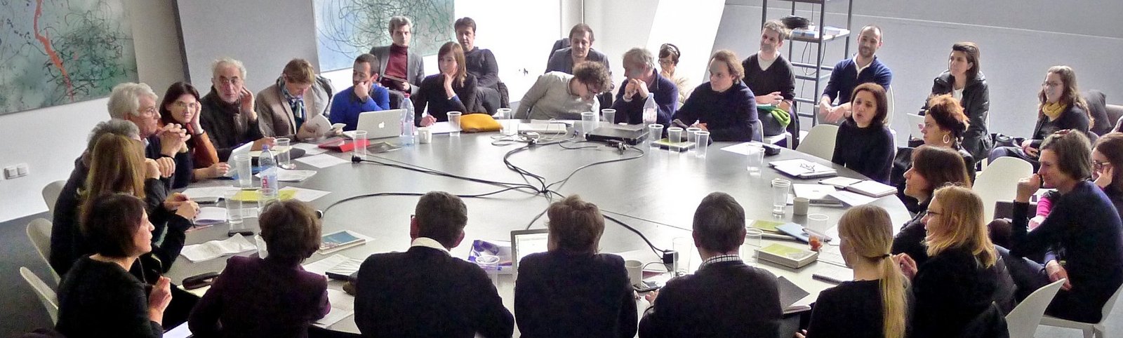 Mediator:innen sitzen um einen großen runden Tisch bei einem internationalen Treffen der Neuen Auftraggeber Antibes/Frankreich