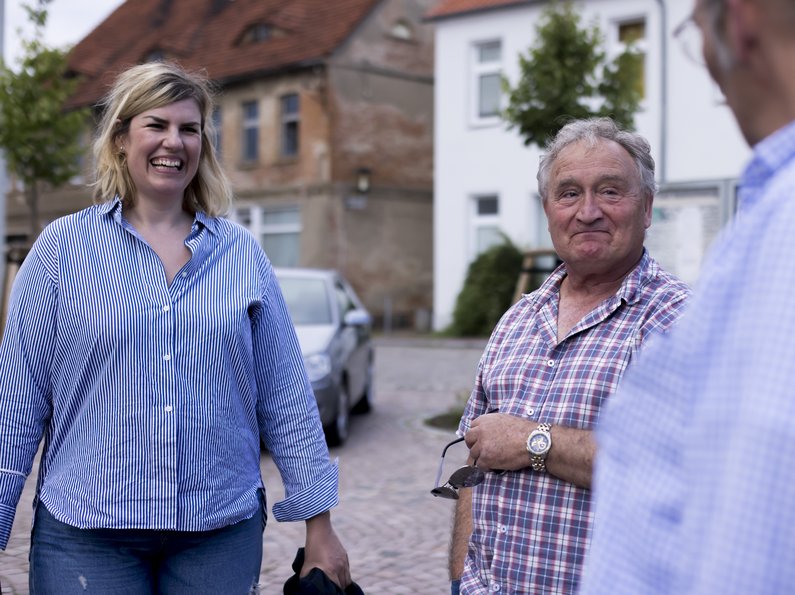 Zwei Personen der Neuen Auftraggeber mit Künstlerin Lena Henke auf der Straße von Penkun