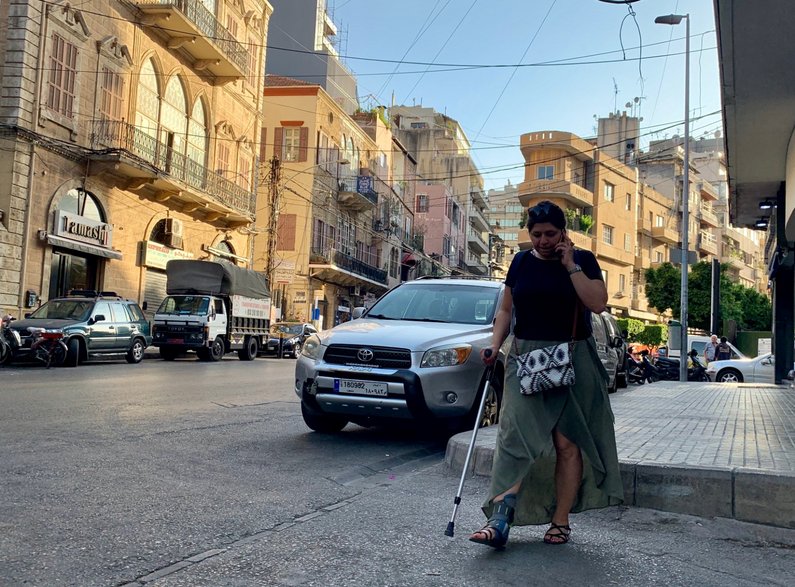 A member of The New Patrons walking along a street lined with cars in Beirut, Lebanon 