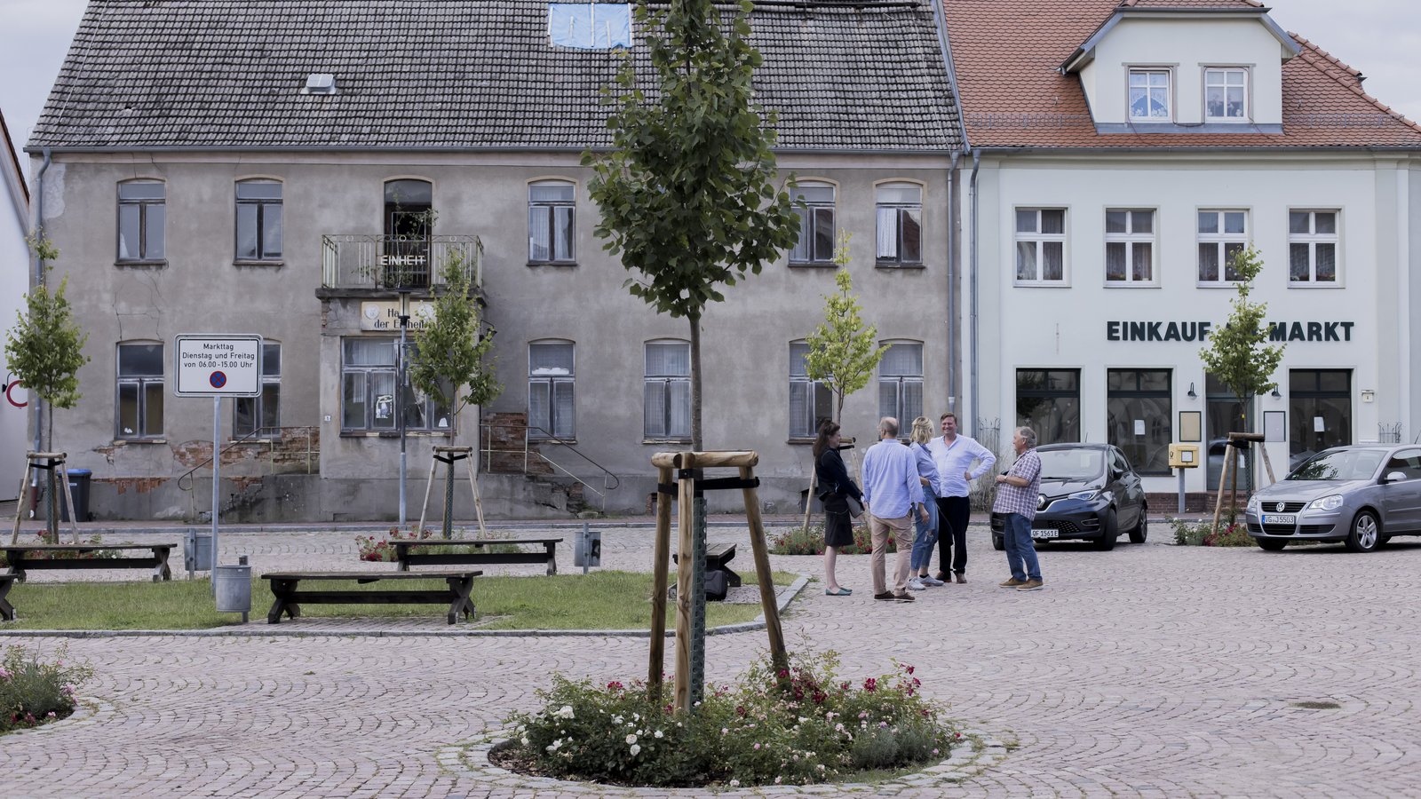 Personen der Neuen Auftraggeber, Häuser und Baum auf dem Marktpatz von Penkun