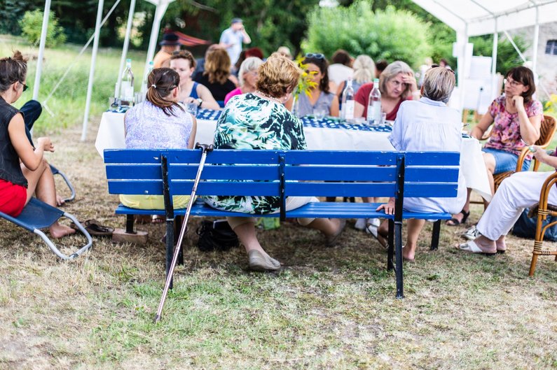 Menschen aus Steinhöfel sitzen auf einer Bank beim Dorfrezepte-Fest