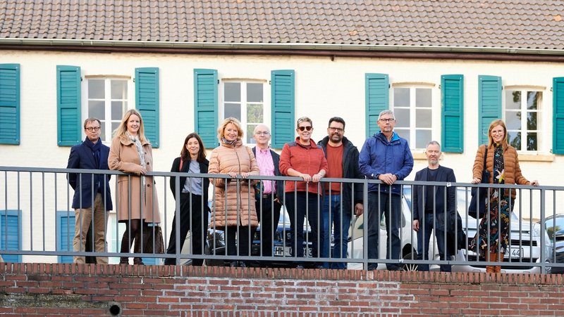 Group photo of the New Patrons of Wickrath in front of a building on the market square