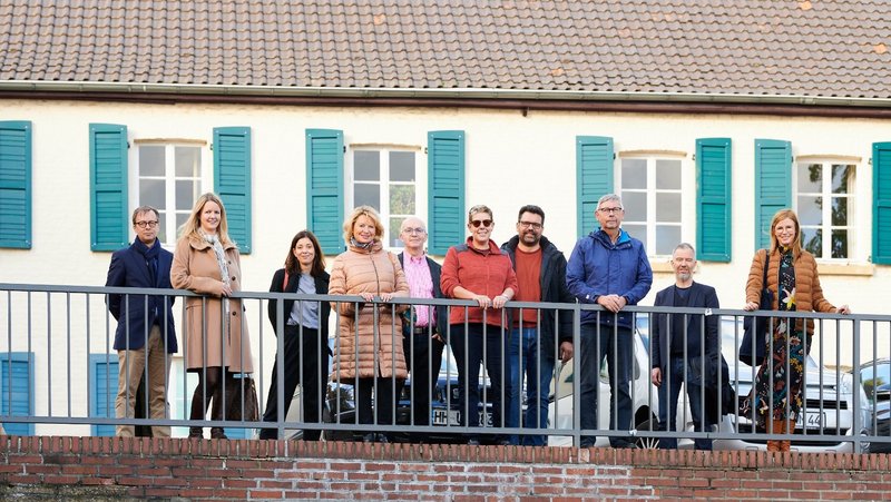 Group photo of the New Patrons of Wickrath in front of a building on the market square
