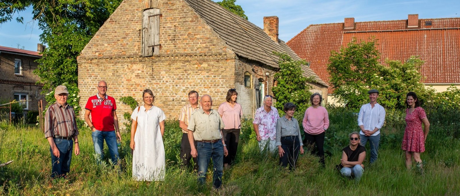 Group photo of The New Patrons of Wietstock in front of an old building in the village