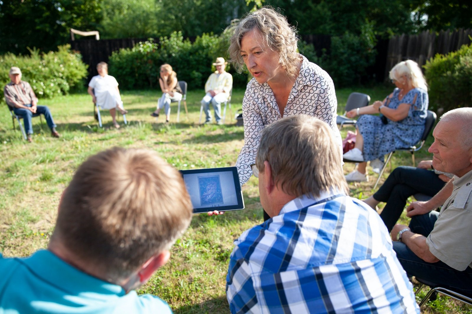 Die Neuen Auftraggeber von Wietstock Mediatorin Susanne Burmester hält ein Ipad und zeigt es zwei Personen der Neuen Auftraggeber von Wietstock