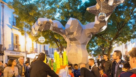 Many people stand around the artwork the Monster of Tours and interact