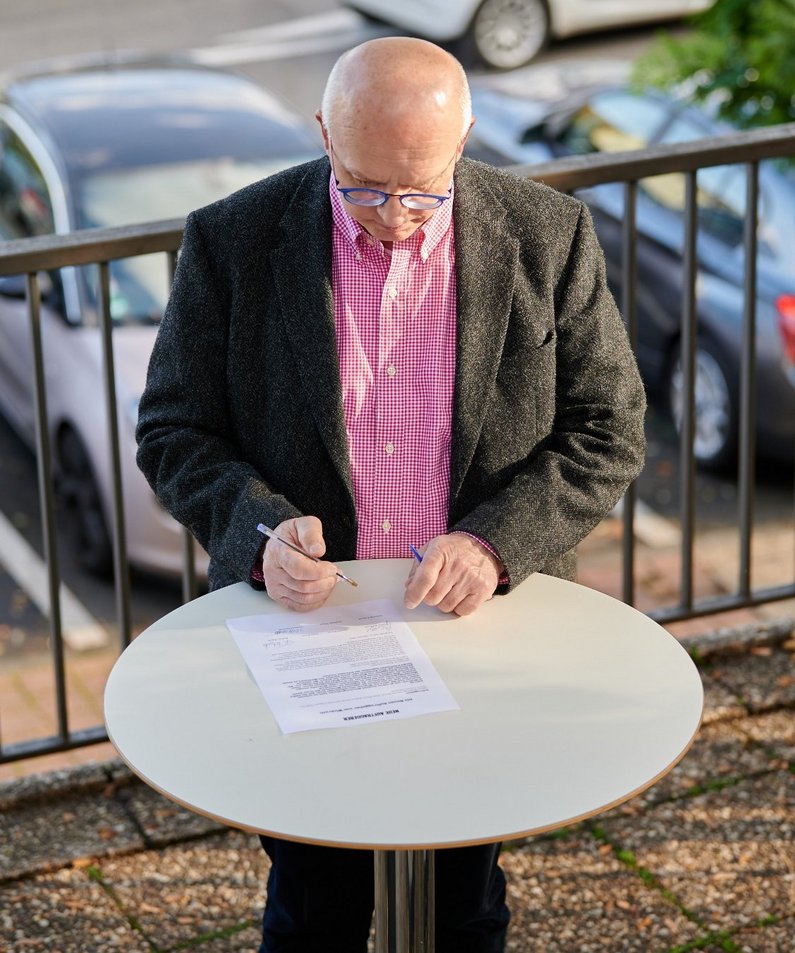Auftraggeber Günter Baldysiak unterzeichnet den Auftrag auf dem Wickrather Marktplatz