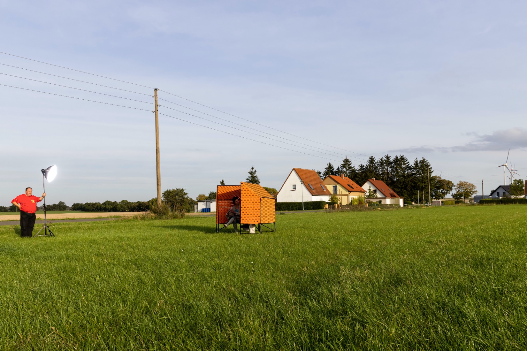 Züsedom-Bank stands in a wide field, a member of The New Patrons lights it up with a spotlight for the photo shoot